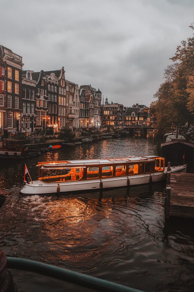 Amsterdam canal boat at dusk with warm city lights