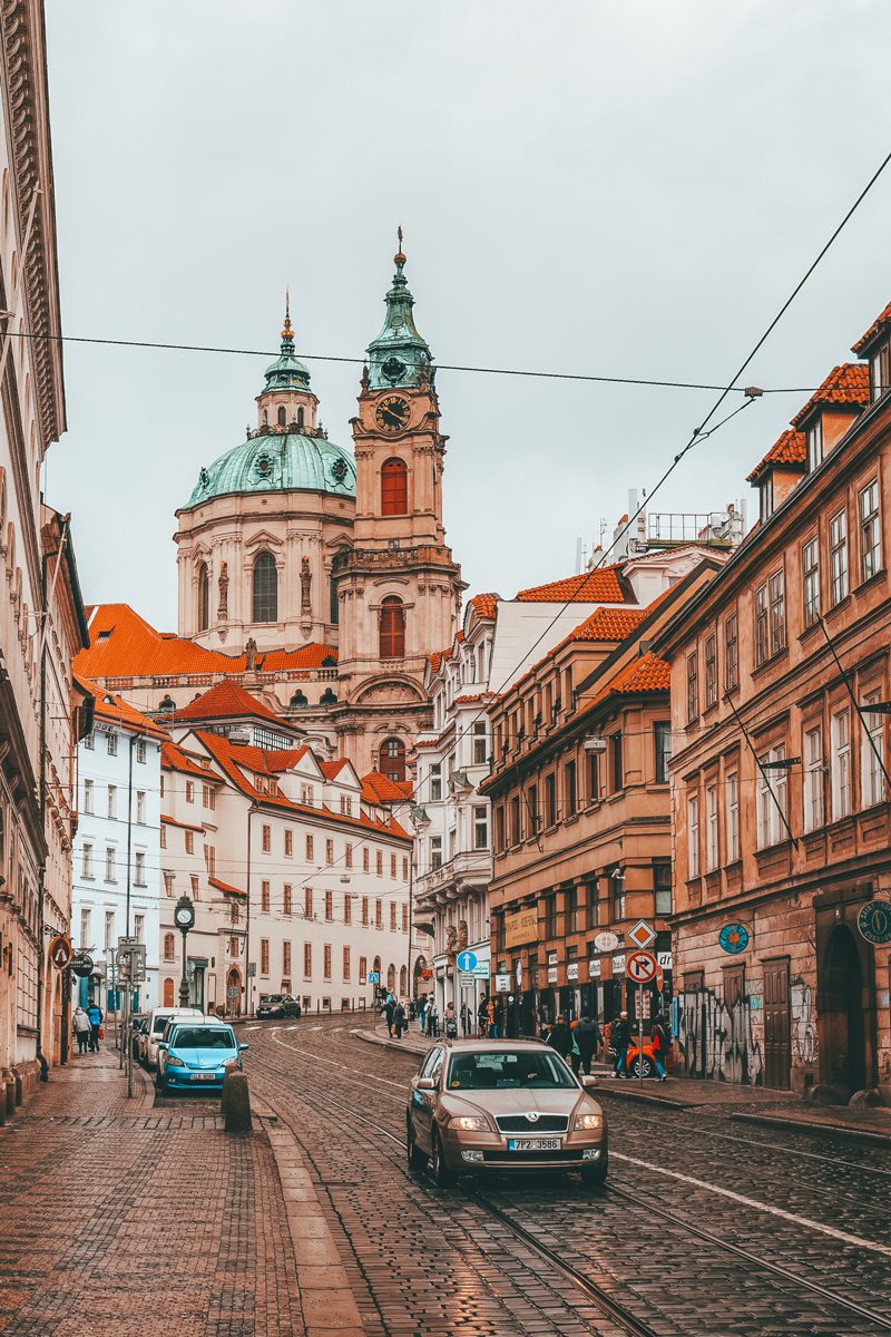 Cobblestone street with St Nicholas Church in Malá Strana, Prague
