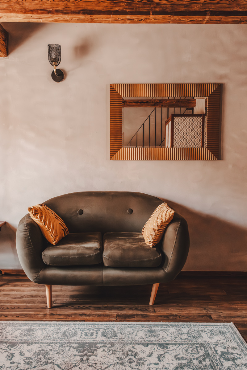 Velvet sofa with amber cushions and framed mirror at Miss Sophie's, Prague