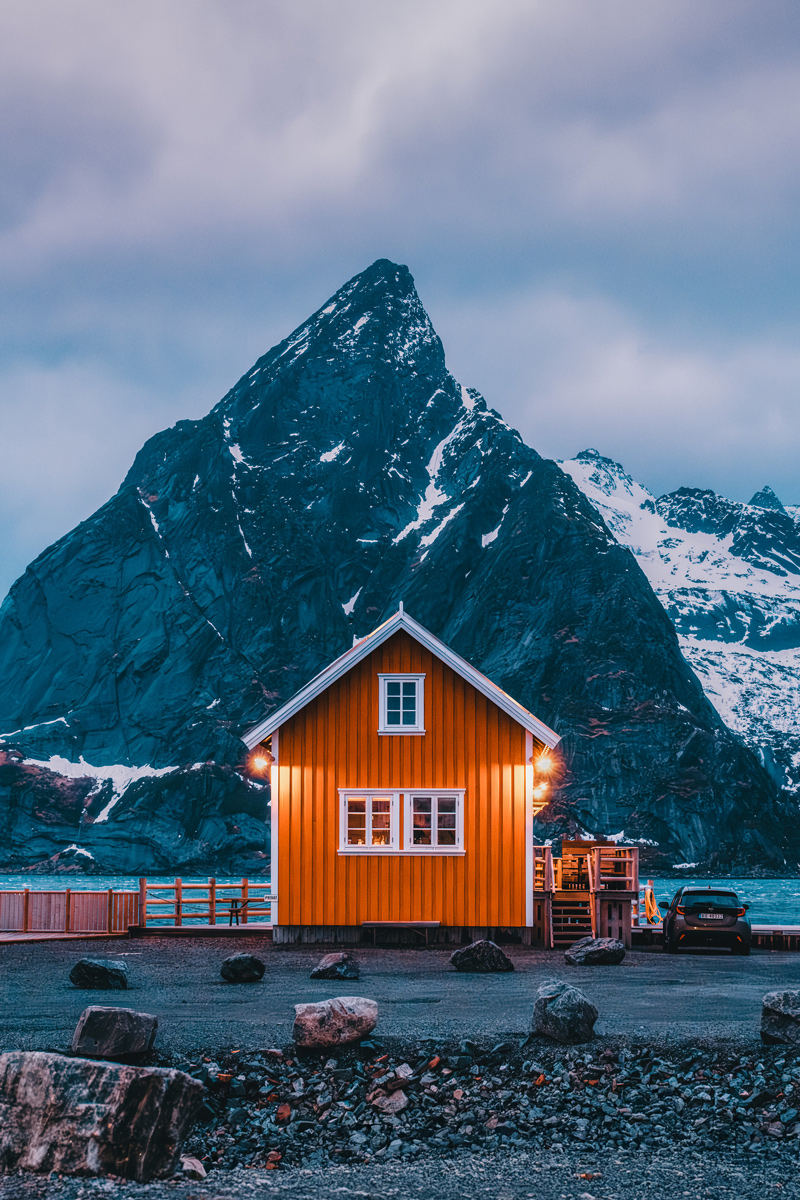 Yellow fishing cabin against dramatic mountain landscape, Sakrisøy, Lofoten
